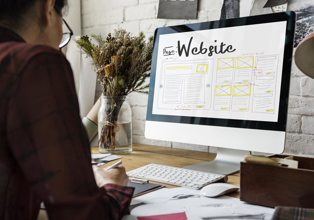 Portfolio clients de l'agence web. un ordinateur de type imac sur un bureau. une personne travaille sur une maquette webdesign. 